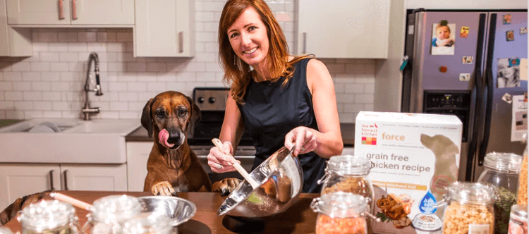 Woman with a mixing bowl in a kitchen with a dog